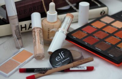 a selection of items from my cruelty free travel makeup bag spread out on a white background with some coffee table books