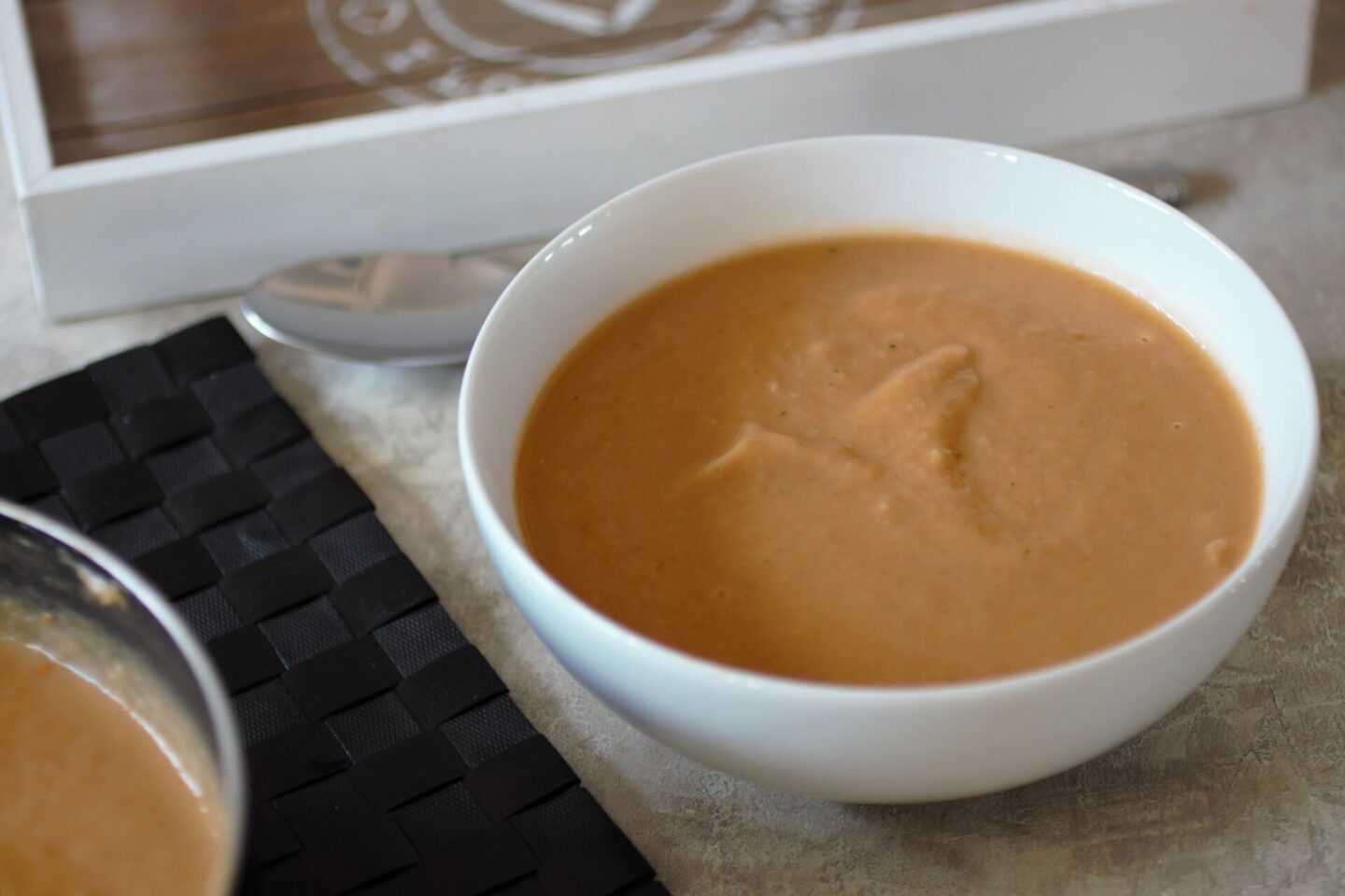 bowl of parsnip and pumpkin soup on a table with pot of soup next to it