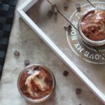 vegan mint chocolate cheesecakes on a table, with some chocolate chips scattered around them.