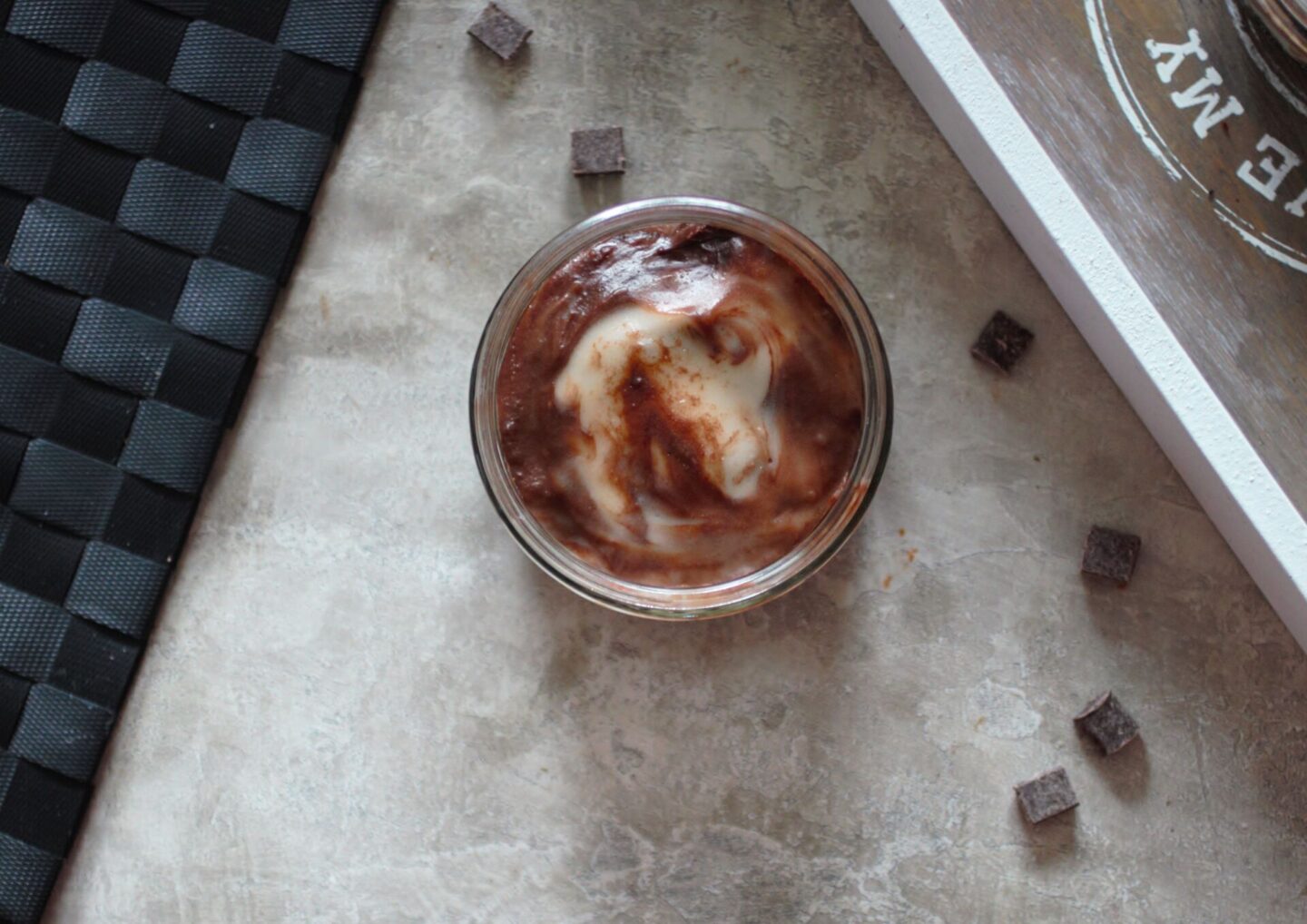 Vegan Mint Chocolate Cheesecake Recipe - one cheesecake in a glass ramekin against a grey background with chocolate chips surrounding it.