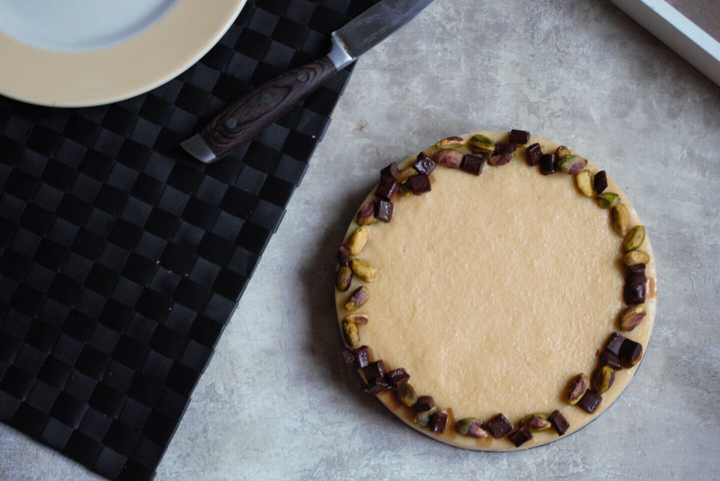 freshly made orange pistachio tart recipe next to a placemat and knife