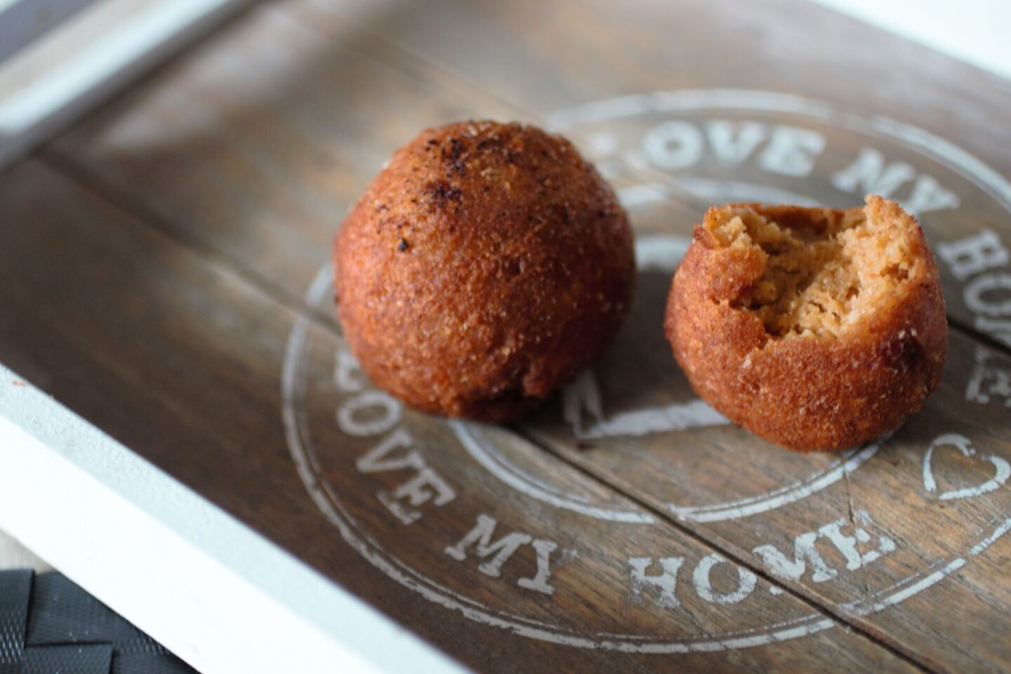 two pumpkin falafels on a grey wooden tray, one cut open to show the inside texture and colour
