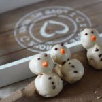 three cookie dough snowmen propped against a tray