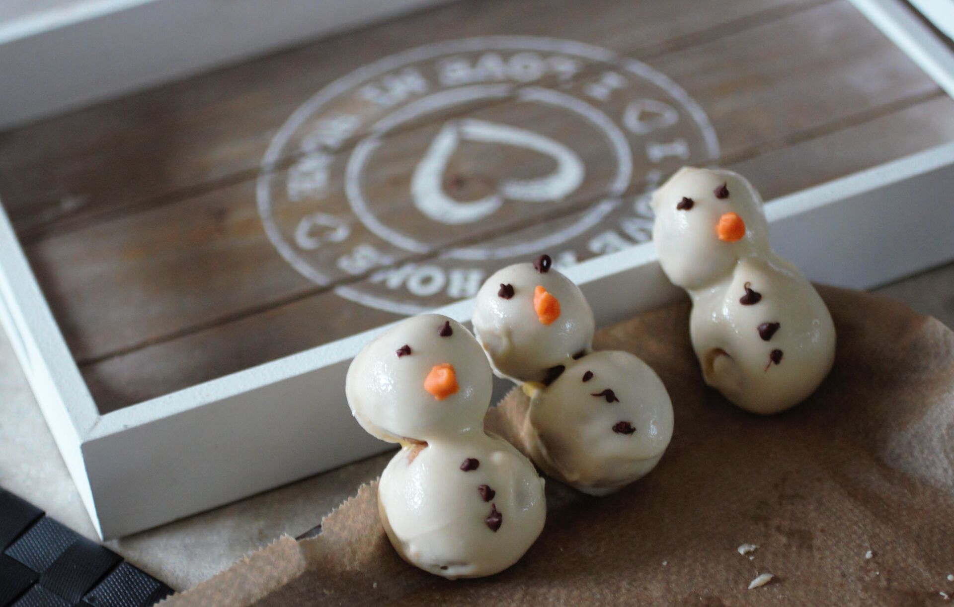 three cookie dough snowmen propped against a tray