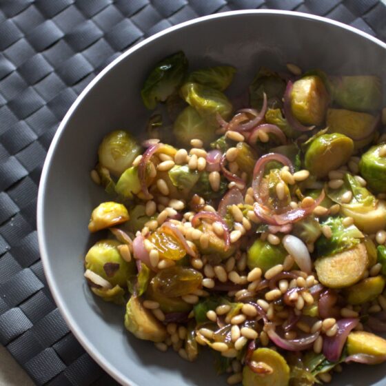 bowl of brussel sprouts agrodolce recipe placed on a black place mat