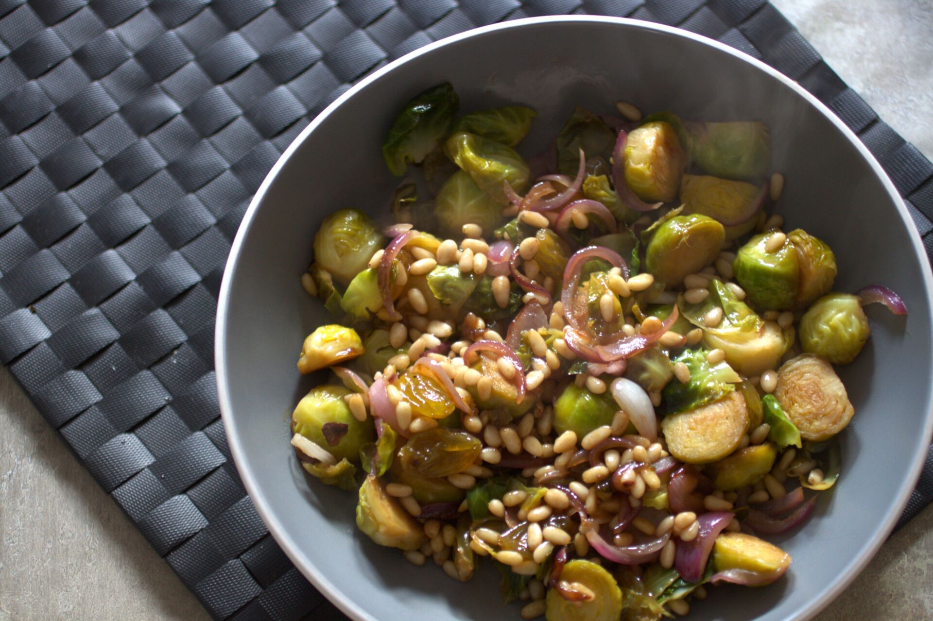 bowl of brussel sprouts agrodolce recipe placed on a black place mat