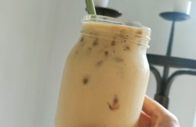 kilner jar filled with tropical breakfast smoothie recipe, being held against a white wall