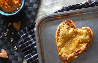 Valentine's Pizza Tart on a baking tray with a pot of sauce placed next to it