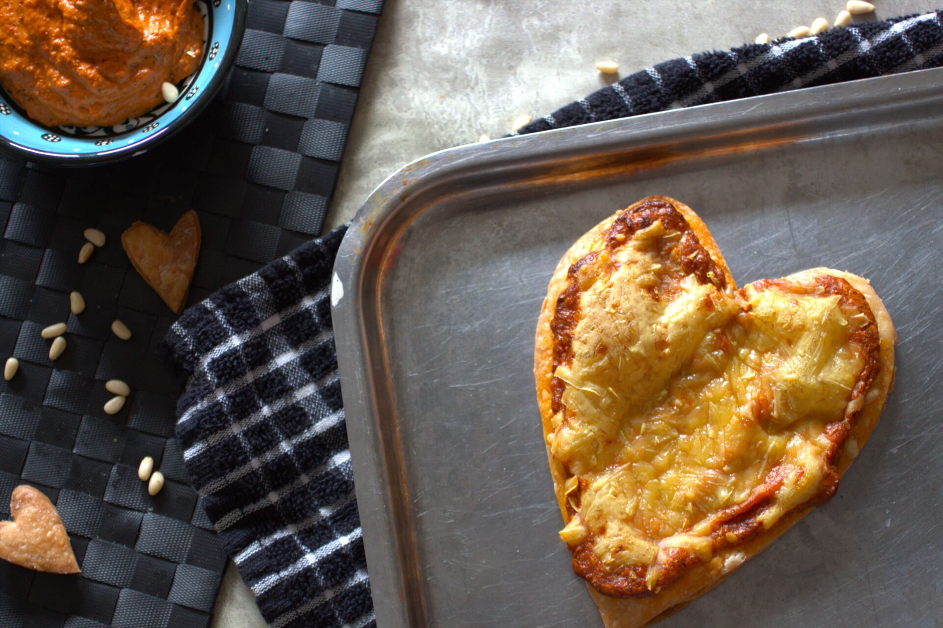 Valentine's Pizza Tart on a baking tray with a pot of sauce placed next to it