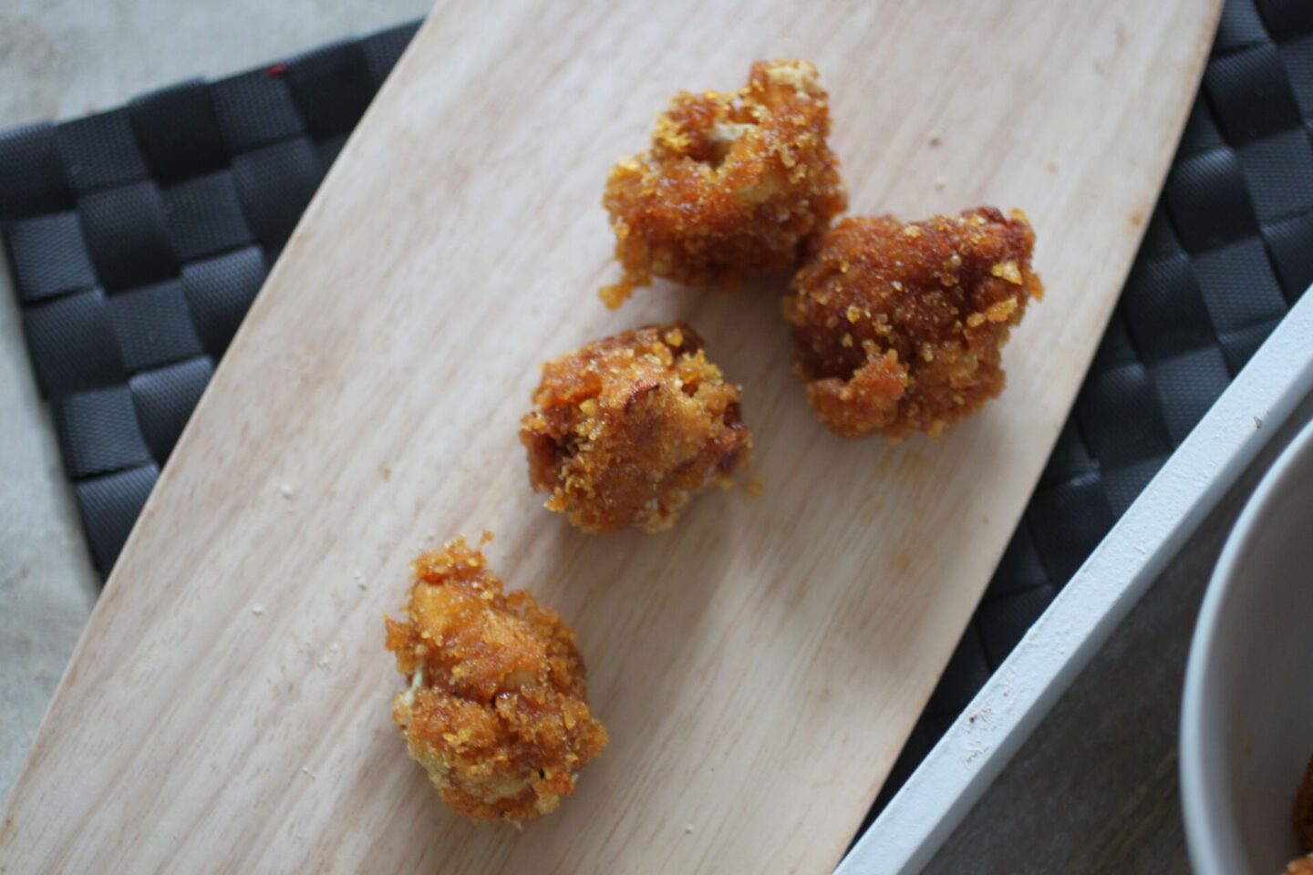 a few pieces of fried barbecue cauliflower on a wooden board