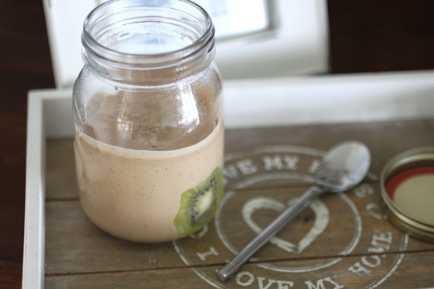 kiwi breakfast pudding in a kilner jar, on a tray with a spoon