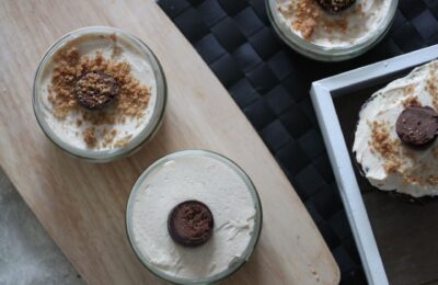 vegan peanut butter cheesecakes in ramekins and a peanut butter easter egg cheesecake on wooden boards