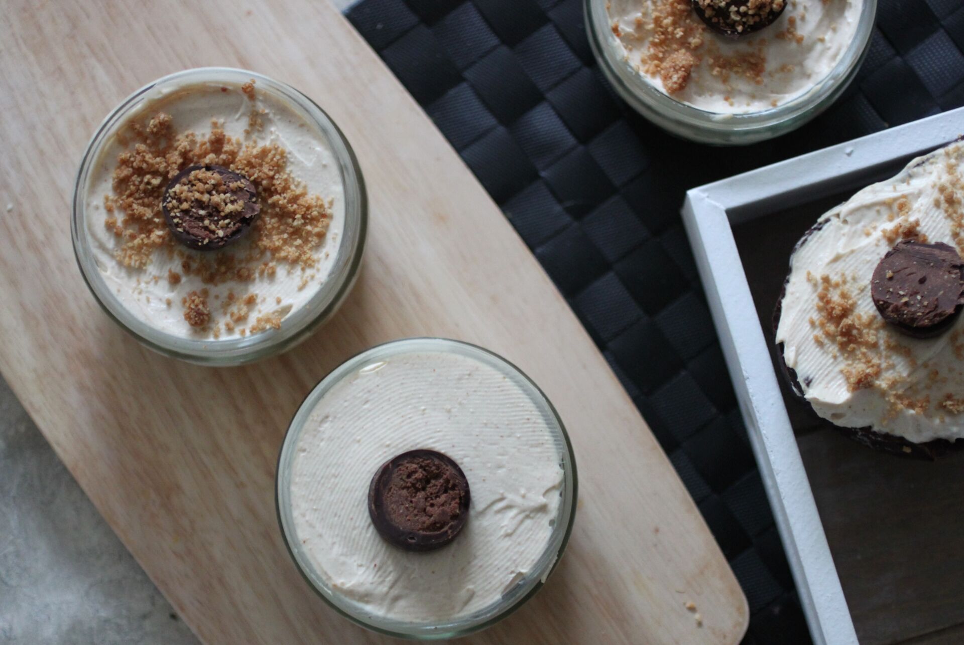 vegan peanut butter cheesecakes in ramekins and a peanut butter easter egg cheesecake on wooden boards