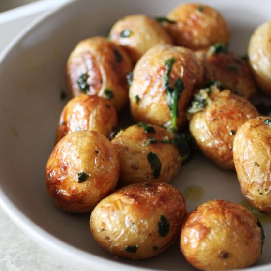 serving bowl filled with garlic herb butter potatoes, showing crispy skins