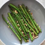 a bowl of grilled asparagus with pine nuts
