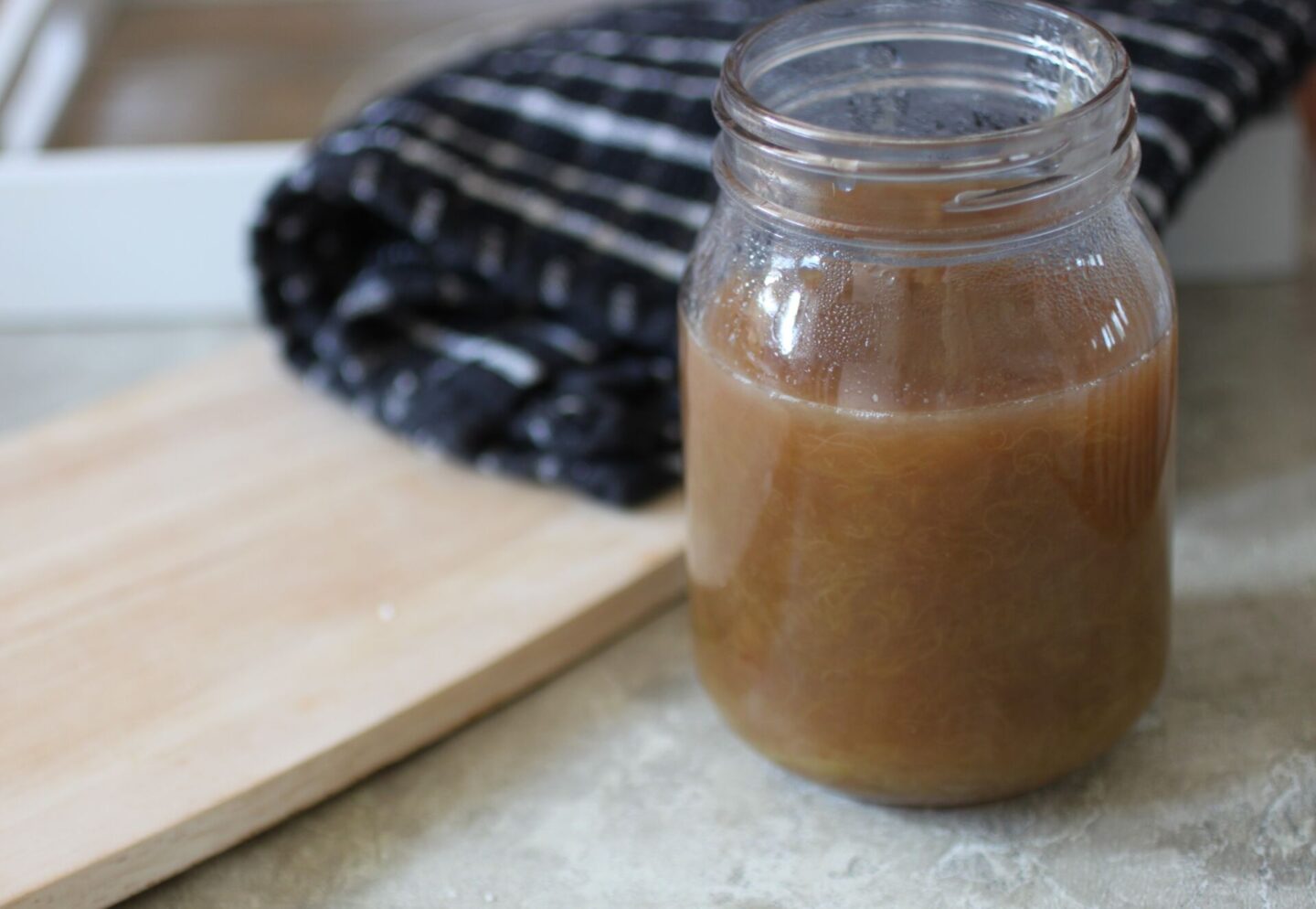 jar of rhubarb compote on a table, next to wooden board