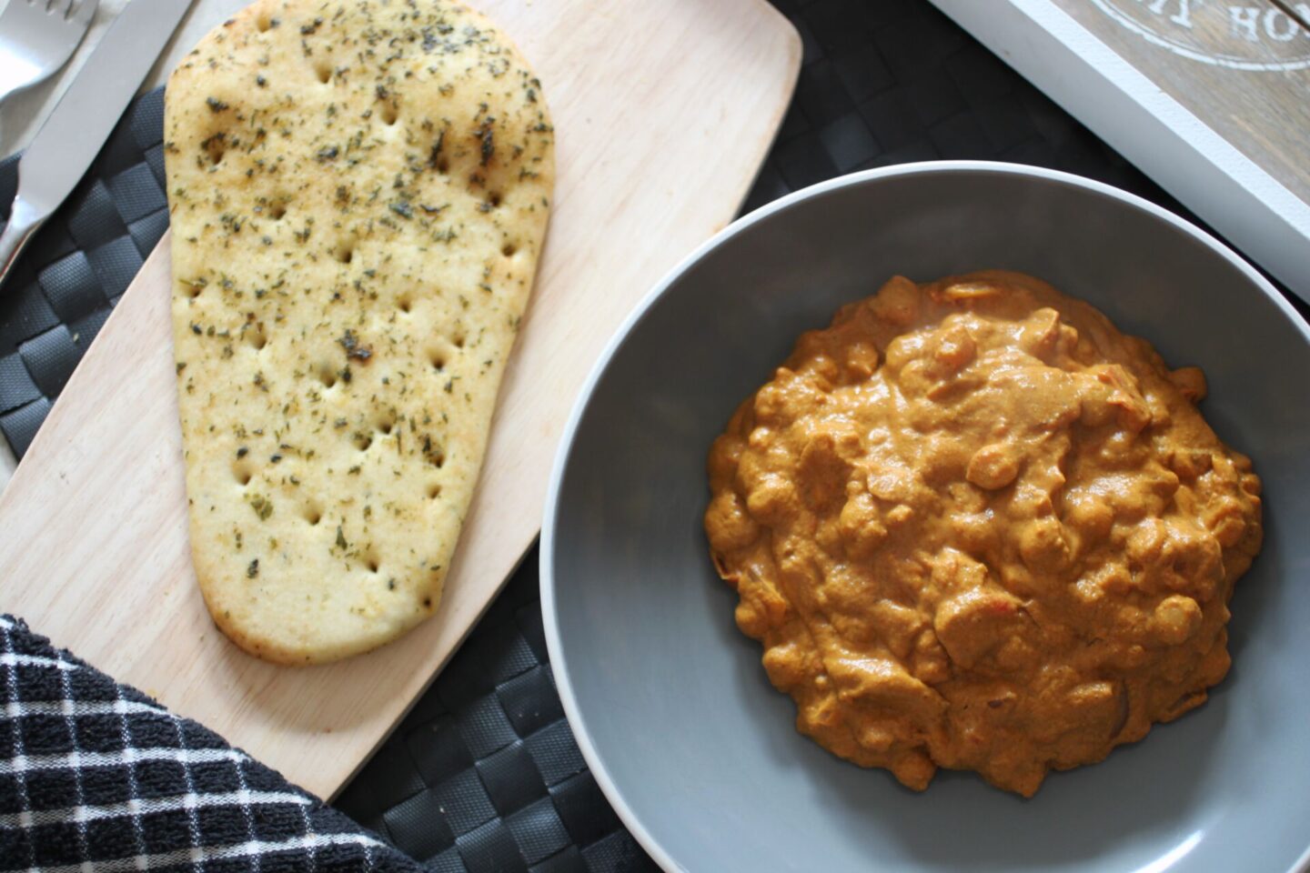 bowl of butter chickpeas placed next to a gluten free naan bread
