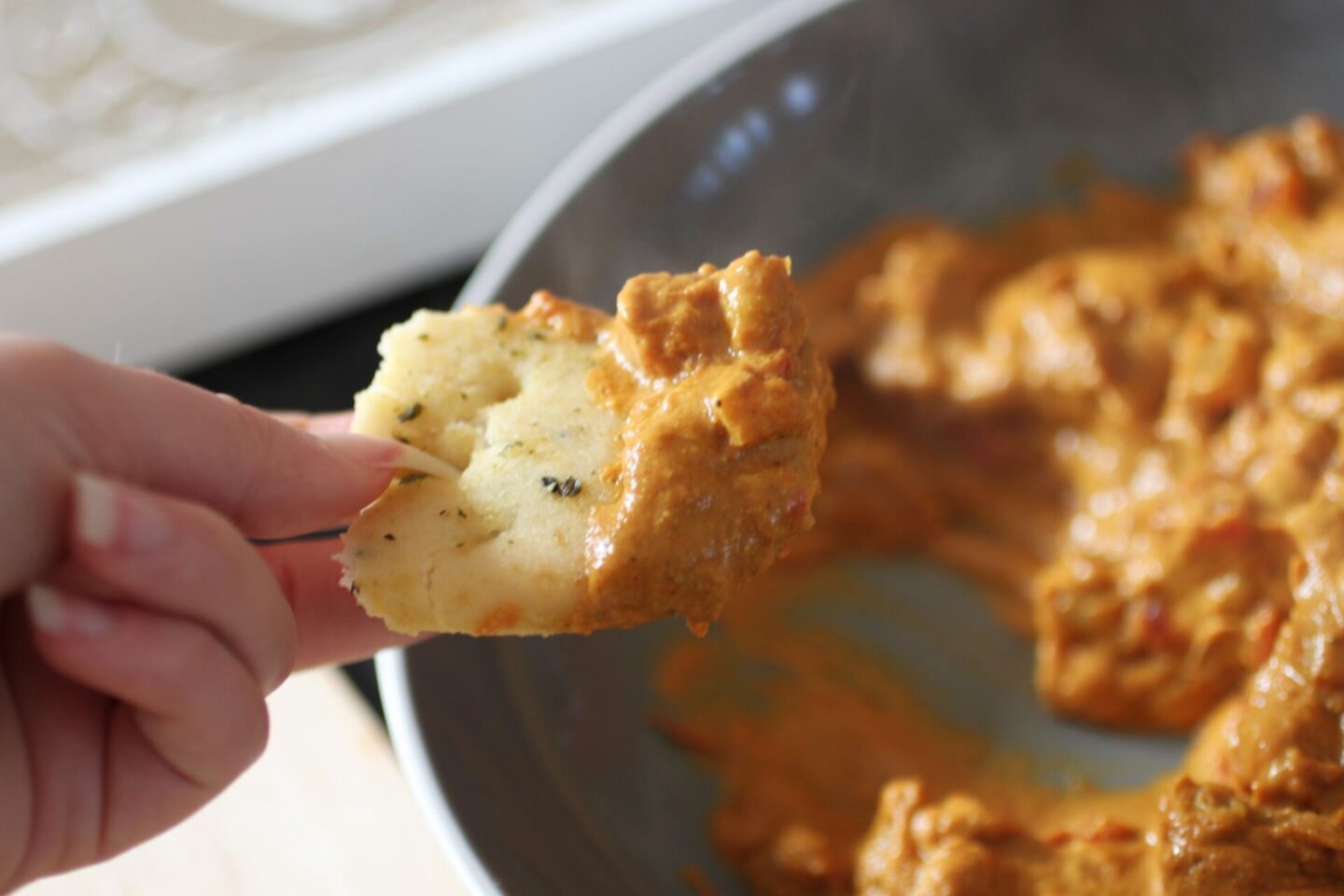 close up shot of gluten free naan bread dunked into butter chickpeas