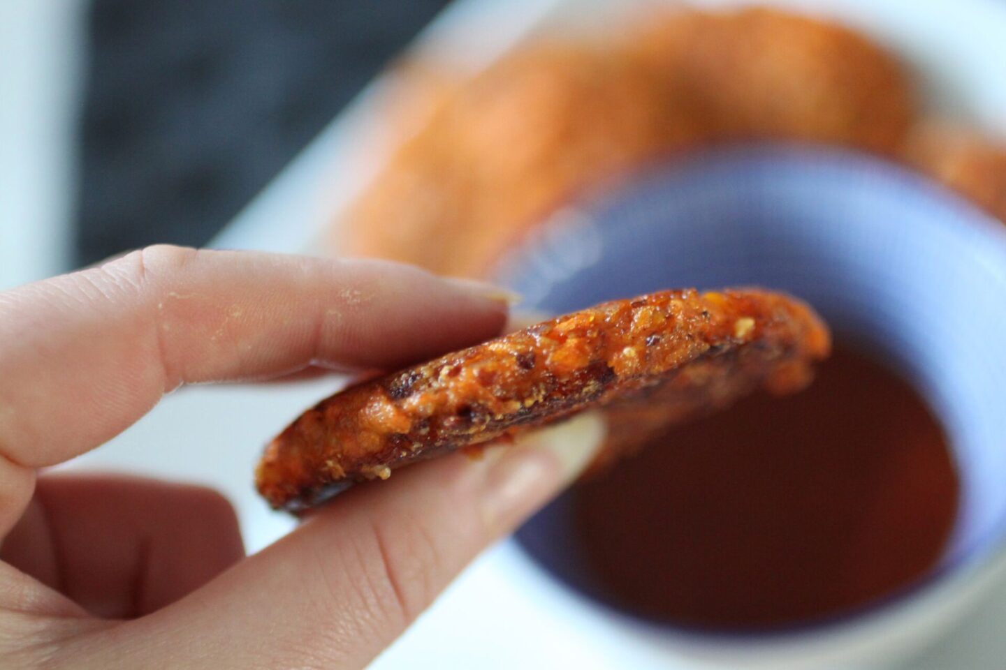 a vegan carrot fritter held up to show the ideal thickness.