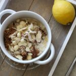 a bowl of lemon breakfast quinoa on a table, shot from above, placed next to a lemon and spoon
