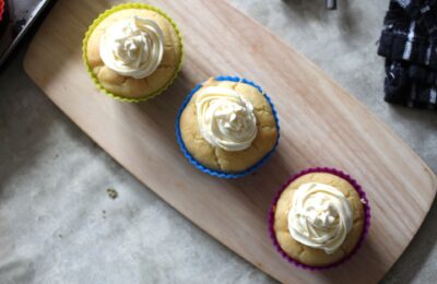 three lemon curd cupcakes on a wooden tray, shot from above.