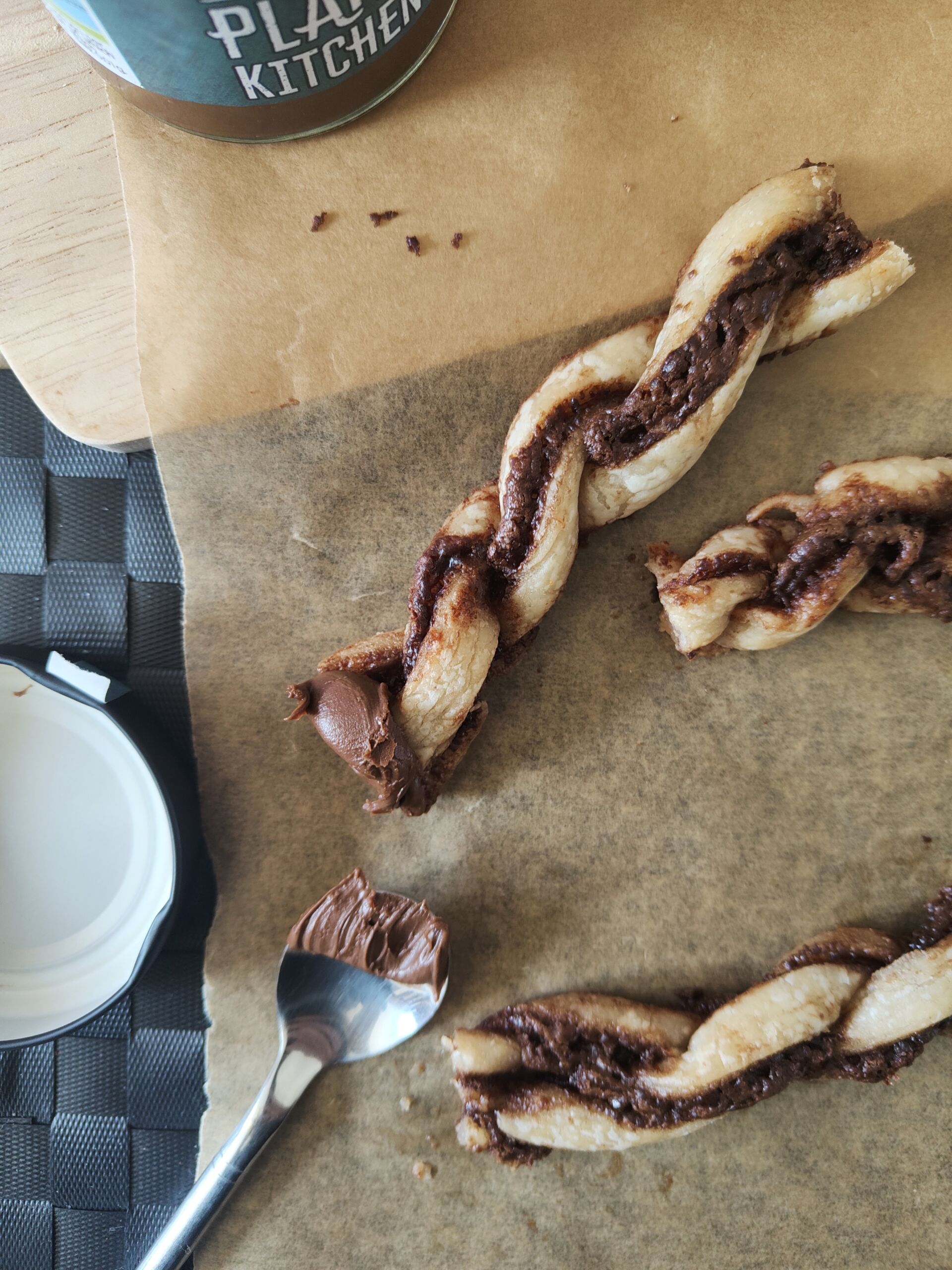 Vegan Nutella Pastry twists on a sheet of greaseproof paper with a spoon of nutella placed next to it