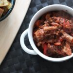 a bowl of jackfruit casserole on a black place mat with some potatoes in a dish to the side