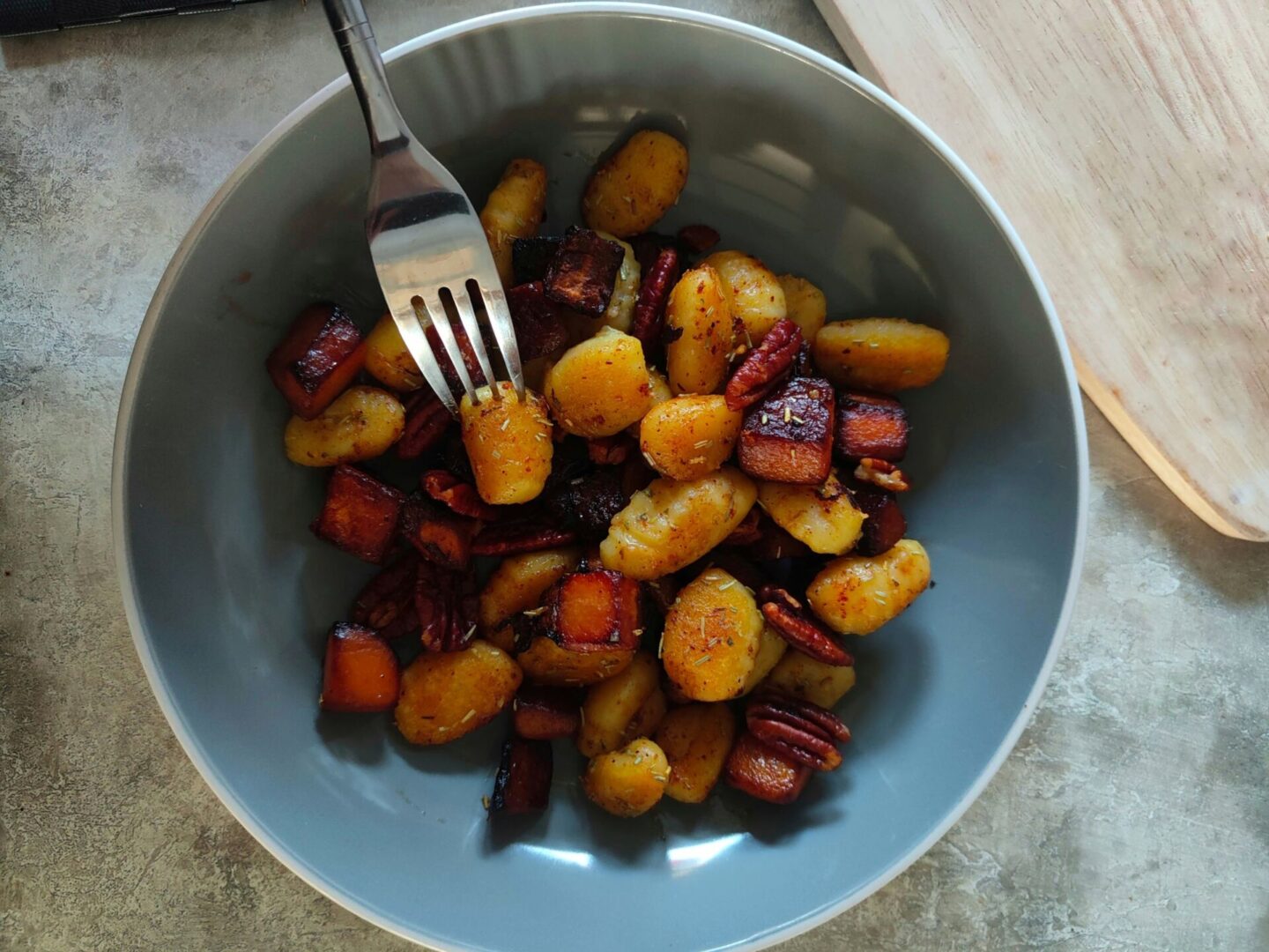 a bowl of butternut squash gnocchi with a fork in it, about to take a piece.