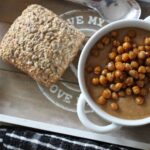 bowl of spiced cauliflower soup with a bread roll beside it, shot from above