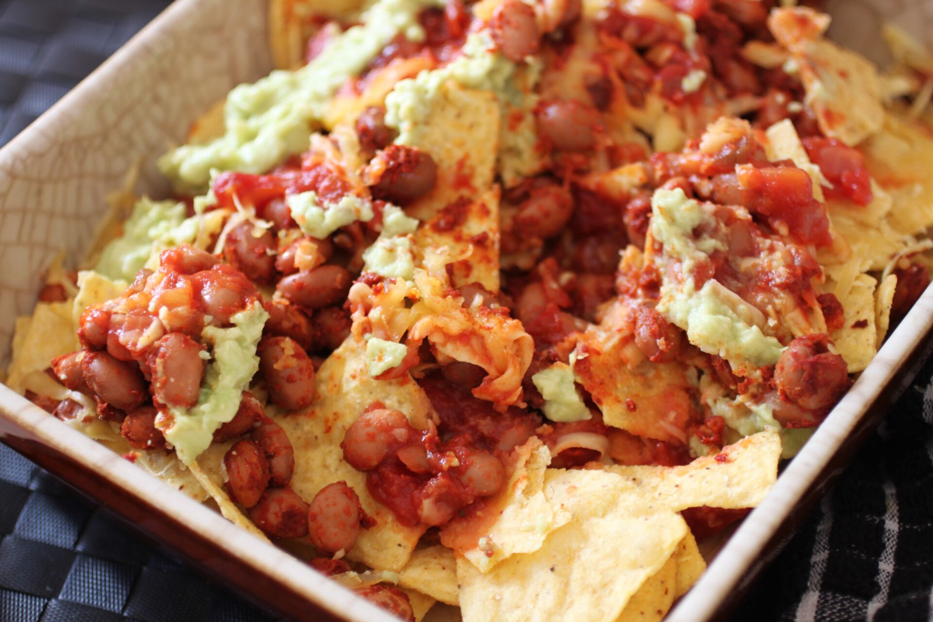 a dish of vegan nachos showing all of the layers