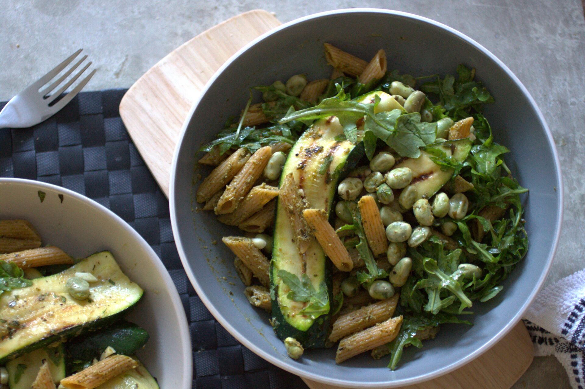 two bowls of grilled greens pasta salad on a dining table