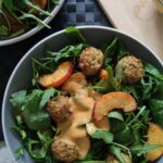 large bowl filled with balsamic baked peach salad and peach salad dressing