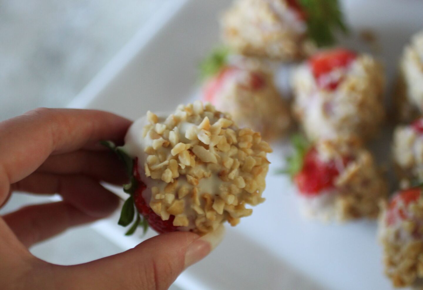 close up of one white chocolate covered strawberry dipped in hazelnuts