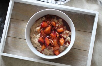 bowl of spiced plum oats on a wooden board, shot from above