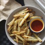bowl of vegan parm fries with chilli sauce