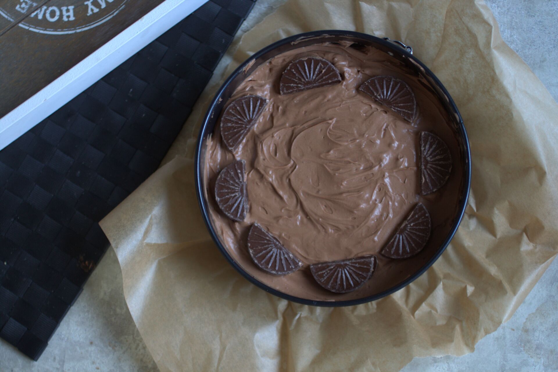 vegan chocolate orange cheesecake in cake tin, on a grey marl background