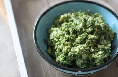 a blue ceramic dish filled with kale pesto