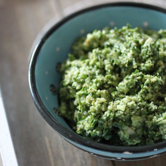 a blue ceramic dish filled with kale pesto