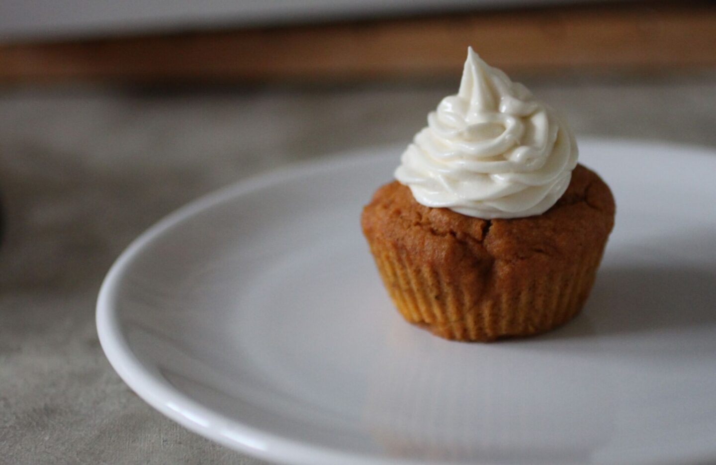 a pumpkin cupcake with cream cheese frosting on a plate