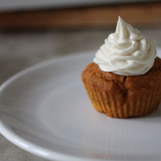 a pumpkin cupcake with cream cheese frosting on a plate