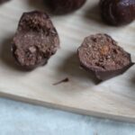 orange nutella truffle sliced open on a wooden board to show inside praline texture