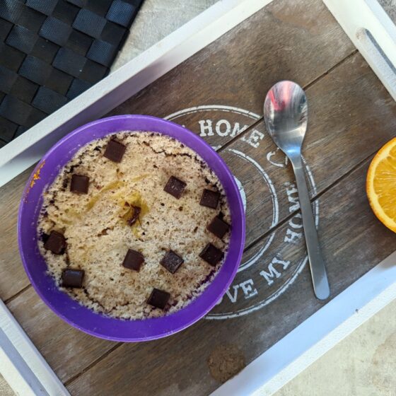 Gluten free vegan orange mug cake recipe placed on a wooden board with half an orange to the side