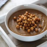 white bowl filled with sweet carrot and lentil soup, topped with roasted chickpeas