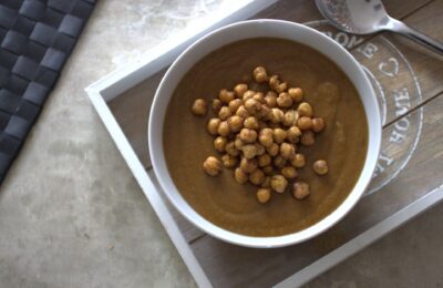 sweet carrot and lentil soup recipe in a white bowl, topped with roasted chickpeas, shot from above