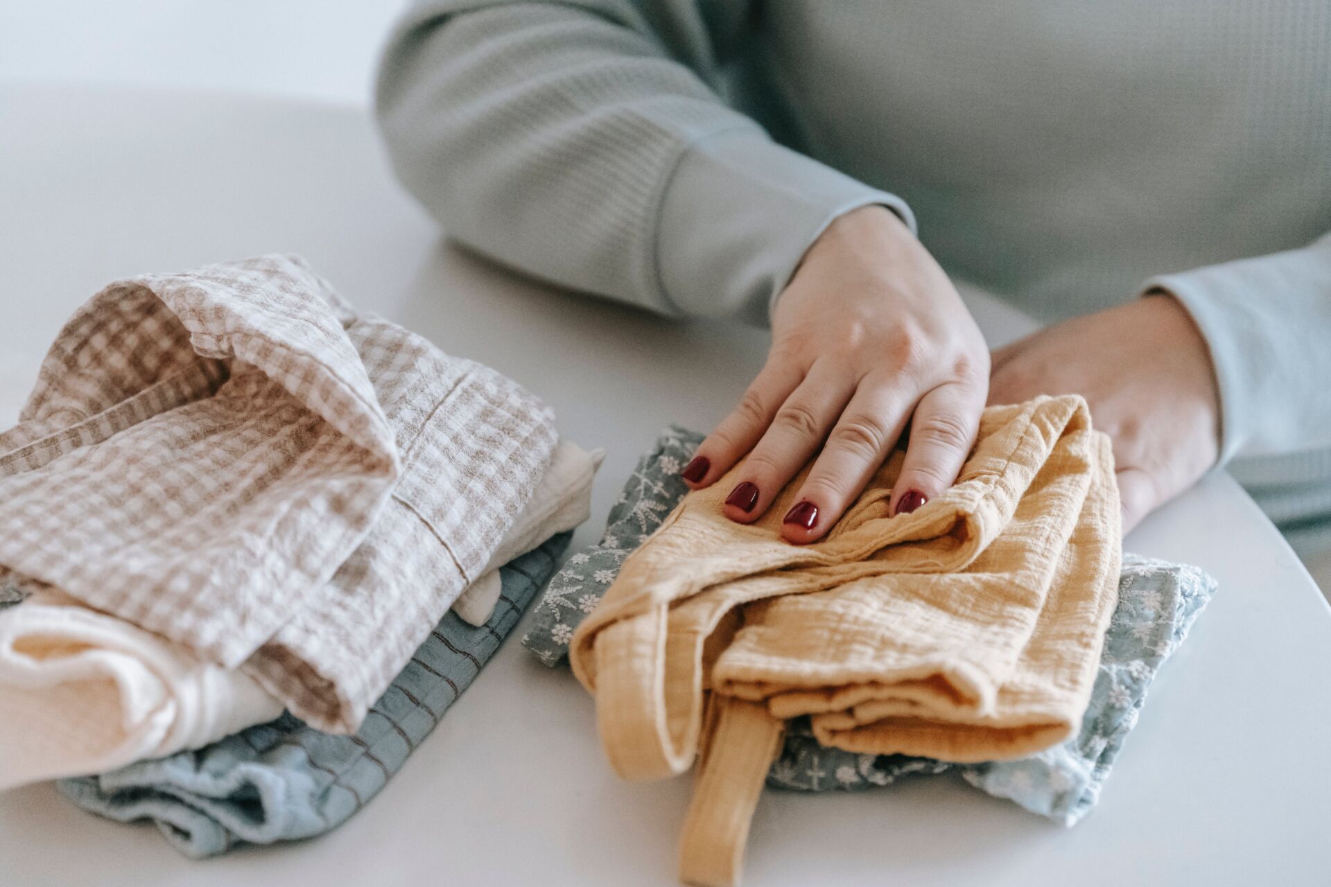a woman folding baby clothes