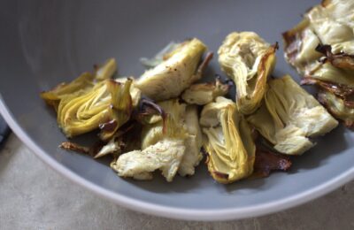close up shot of roasted artichoke hearts in grey bowl