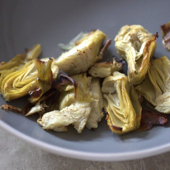close up shot of roasted artichoke hearts in grey bowl