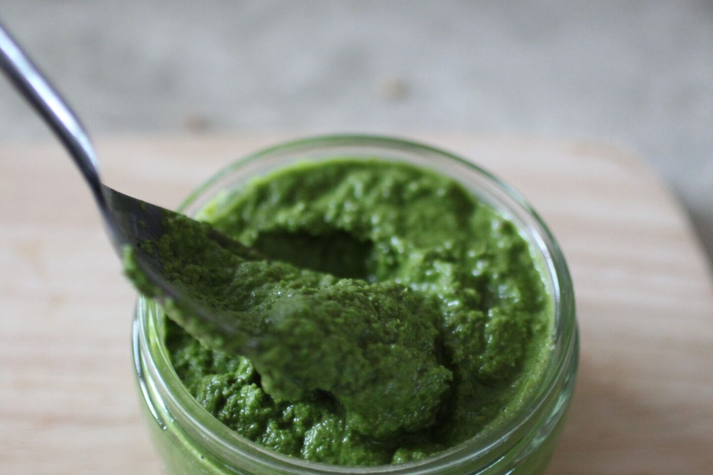 pot of lemon kale dressing with a spoon in it showing the texture