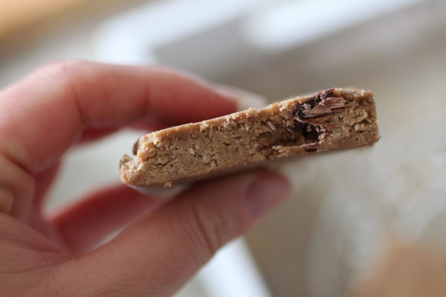 close up of a peanut butter protein bar held up to show the texture