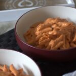 bowl of creamy tomato pasta placed on a dining table, shot from the side